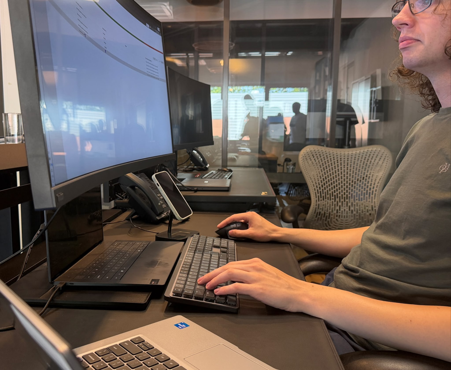 Employee working at a fully managed desk with monitor, keyboard, mouse and desk phone