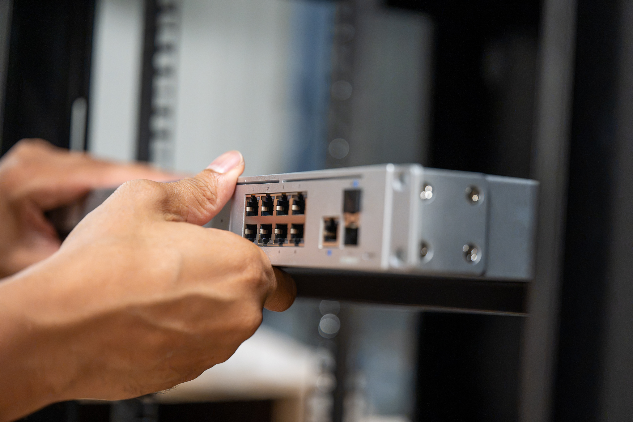 Technician sliding a switch into a rack during an internet installation